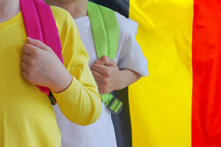 Two children with satchels background of Belgium flag. Concept of upbringing and educating children in Belgiumの写真素材