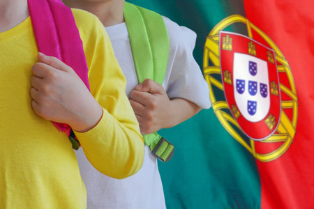 Two children with satchels background of Portugal flag. Concept of upbringing and educating children in Portugalの写真素材