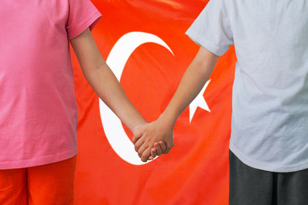 Two children joined hands on flag Turkey background. Boy and girl joined hands on background flag of Turkey. Concept of family and parenting in Turkeyの写真素材