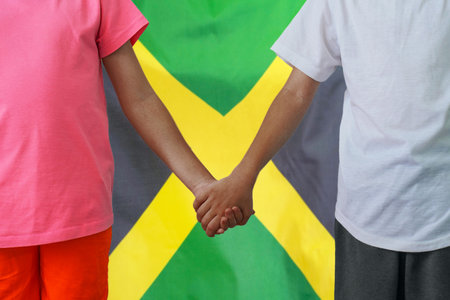 Two afro children joined hands on flag Jamaica background. Boy and girl joined hands on background flag of Jamaica. Concept of family and parenting in Jamaicaの写真素材