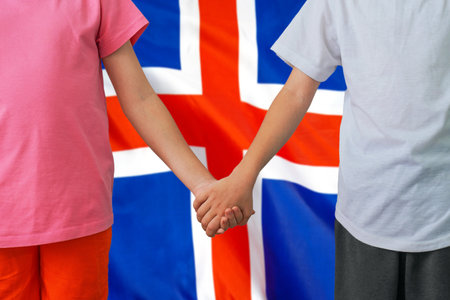 Two children joined hands on flag Iceland background. Boy and girl joined hands on background flag of Iceland. Concept of family and parenting in Icelandの写真素材