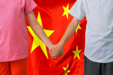 Two children joined hands on flag China background. Boy and girl joined hands on background flag of China. Concept of family and parenting in Chinaの写真素材