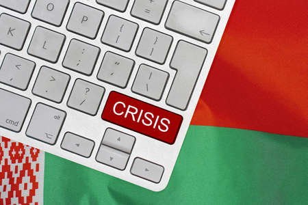 White computer keyboard with red button with word of crisis on Belarus flag background. Global economic, political and financial crisis. Economic crisis and economic recession in Belarusの写真素材