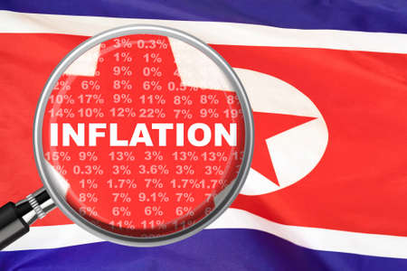 Magnifying glass focused on the word inflation on North Korea flag background. Hike interest rate. inflation income crisis. Inflation, tax, cash flow and another financial concept in North Koreaの写真素材