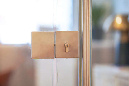 Door lock and doorknob on close glass door in office. Detail of contemporary door lock with doorknob for a glass door in officeの写真素材