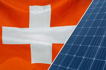 Solar panels against flag Switzerland background. Solar battery generates a pure electricity. Concept of sustainable resources and renewable energy in Switzerlandの写真素材