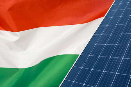 Solar panels against flag Hungary background. Solar battery generates a pure electricity. Concept of sustainable resources and renewable energy in Hungaryの写真素材
