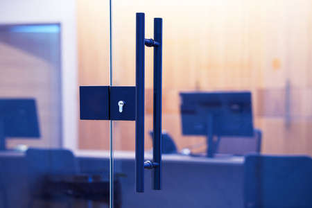 Door lock and doorknob on close glass door in office. Detail of contemporary door lock with doorknob for a glass door in officeの写真素材