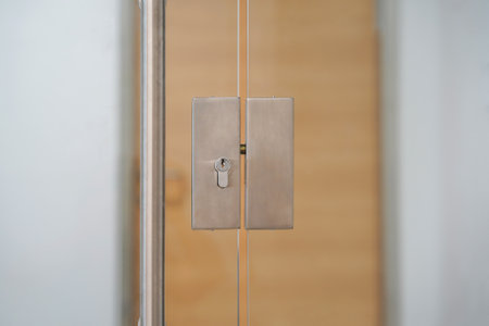 Door lock and doorknob on close glass door in office. Detail of contemporary door lock with doorknob...