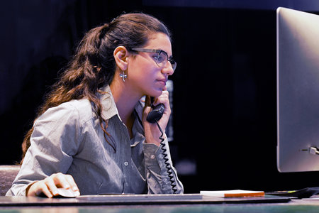Portrait of woman secretary answering phone calls and talking with customers looking at computer on desk tableの写真素材