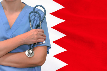 Female surgeon or doctor with stethoscope in hand on flag of Bahrain background. Surgery concept in Bahrainの写真素材