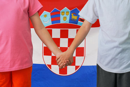 Two children joined hands on flag of Croatia background. Boy and girl joined hands on background flag of Croatia. Concept of family and parenting in Republic of Croatiaの写真素材