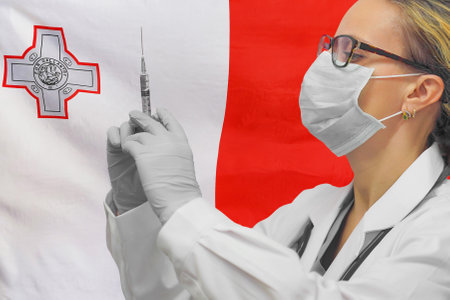 Female doctor or nurse in gloves holding syringe for vaccination against flag of Malta background. Medicine concept and fight the virus. Coronavirus in Republic of Maltaの写真素材