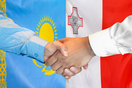 Business handshake on background of two flags. Men handshake on background of Kazakhstan flag and flag of Malta. Support conceptの写真素材