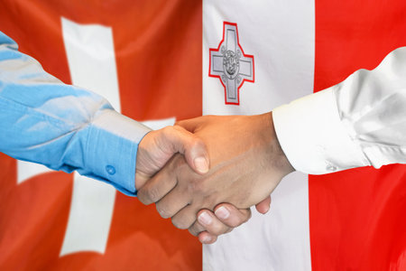 Business handshake on background of two flags. Men handshake on background of Switzerland flag and flag of Malta. Support conceptの写真素材
