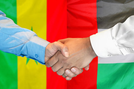 Business handshake on background of two flags. Men handshake on flag of United Arab Emirates and Senegal flag background. Support conceptの写真素材