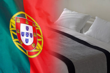 Hotel bed on the background of the Portugal flag. Tourism and hotel business in the Portugalの写真素材