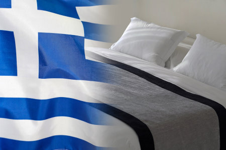 Hotel bed on the background of the Greece flag. Tourism and hotel business in Greeceの写真素材