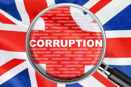 Magnifying glass focused on the word corruption on UK flag background. Corruption and another financial concept in United Kingdomの写真素材