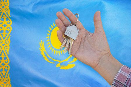 Hand shows the keys to the apartment on background of flag Kazakhstan. Keys to the apartment in a female hand on background of flag Kazakhstan. Realty concept new apartment in Kazakhstanの写真素材