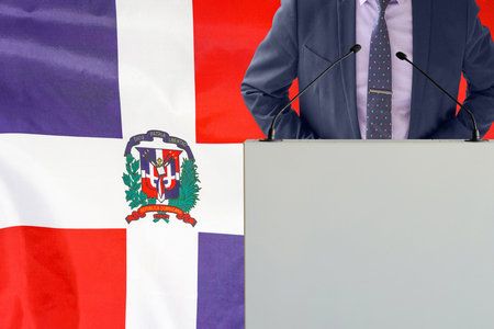 Tribune with microphone and man in suit on Dominican Republic flag background. Businessman and tribune on Dominican Republic flag backgroundの写真素材