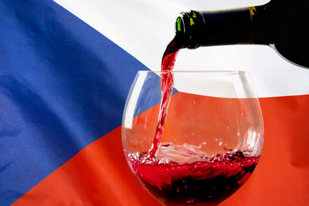 Red wine pouring from a bottle into a glass against the background of the Czech Republic flag. Concept of winemaking and wine export in Czech Republicの写真素材