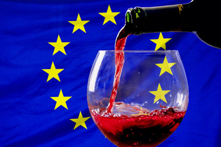 Red wine pouring from a bottle into a glass against the background of the EU flag. Concept of winemaking and wine export in European Unionの写真素材