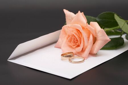 Rose, envelopes and wedding rings on a black backgroundの写真素材