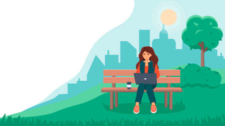 A young woman sits on a bench in a park and works on a laptop . The concept of freelance or online...