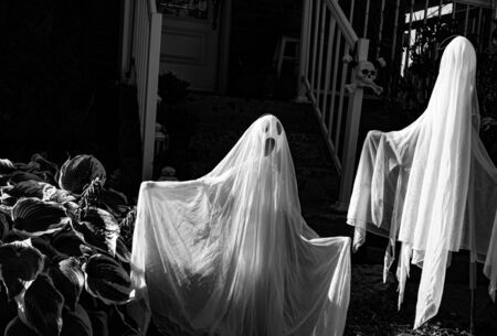 Halloween decoration at the front yard doors.creepy ghosts on the dark stairs background.Scary...
