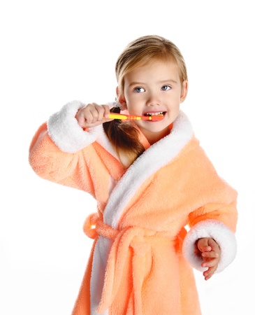 Little girl in dressing gown brushing her teeth isolated on white background の写真素材
