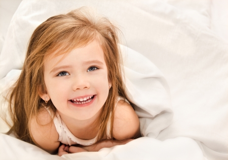 Adorable little girl awaked up in her bed の写真素材
