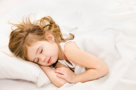 Adorable little girl sleep in the bed の写真素材