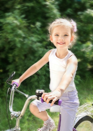 Smiling cute little girl with her bicycle outdoorsの写真素材