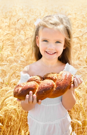 Happy girl on field of wheat with bread の写真素材