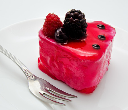 Fruit jelly cake and fork on the plate isolated on a white background