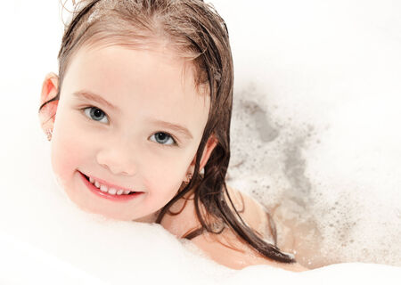 Smiling little girl washing in bath with foam closeup