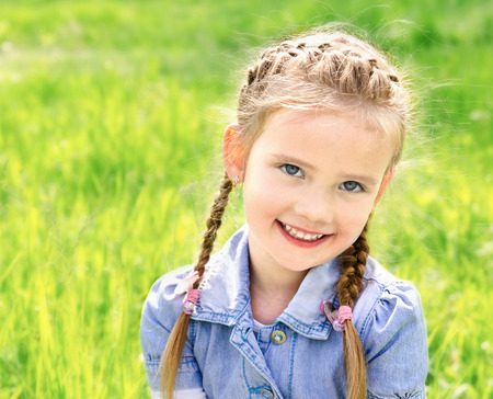 Portrait of adorable smiling little girl on the meadow outdoorの写真素材