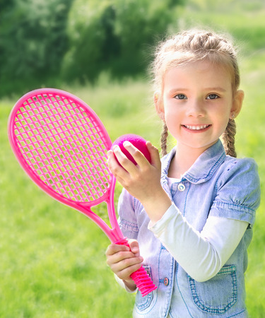 Adorable smiling little girl with racket and ball outdoorの写真素材
