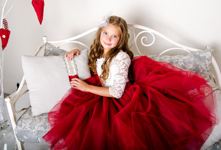 Adorable smiling little girl child in princess dress sitting on the sofaの写真素材