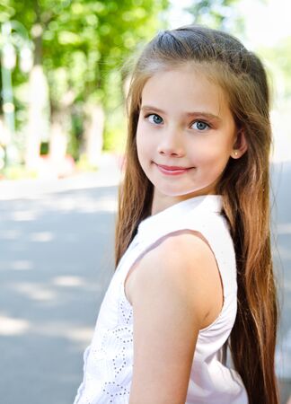 Portrait of adorable smiling little girl child schoolgirl teenager outdoors in summer dayの写真素材