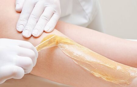Cosmetologist beautician waxing female legs in the spa center beauty salon depilation epilation cosmetology conceptの写真素材