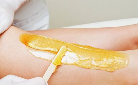 Cosmetologist beautician waxing female legs in the spa center beauty salon cosmetology conceptの写真素材