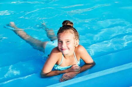 Cute smiling little girl child having fun in the swimming pool on summer vacation