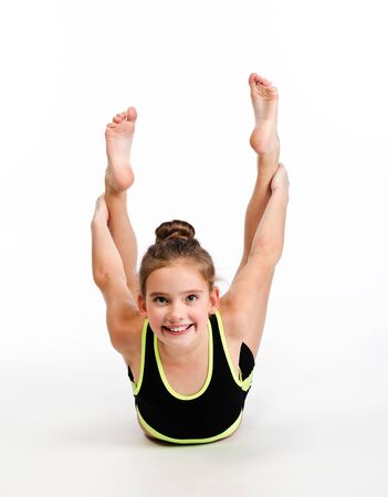 Flexible cute happy little girl child gymnast doing acrobatic exercise isolated on a white background. Sport, training, fitness, active lifestyle conceptの写真素材