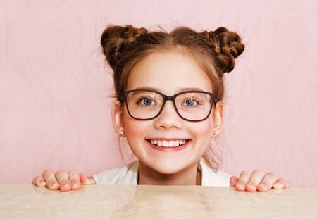 Cute little girl child preteen in eyeglasses education, school and vision concept isolated on a pinkの写真素材