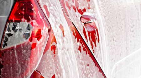 Manual car wash cleaning with foam and pressured water at service station outdoorの写真素材