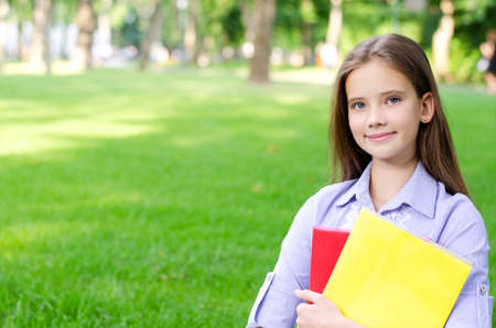 Back to school. Education concept. Cute smiling schoolgirl holding the books outdoor. Happy little...