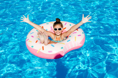 Cute smiling little girl in swimming pool with rubber ring. Child having fun on vacation in summertimeの写真素材