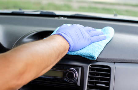 Cleansing car interior. Male hand in protective glove disinfecting vihicle inside for protection...